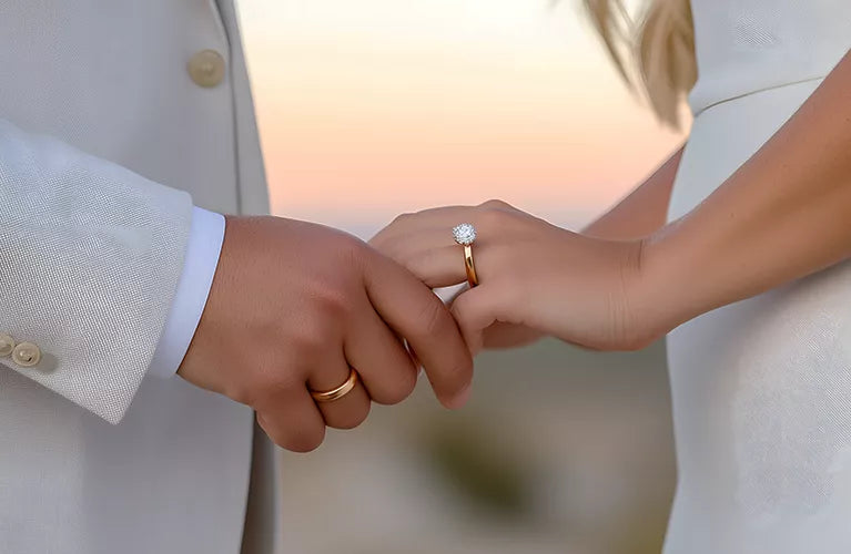 Two people holding hands with wedding rings on a blurred background